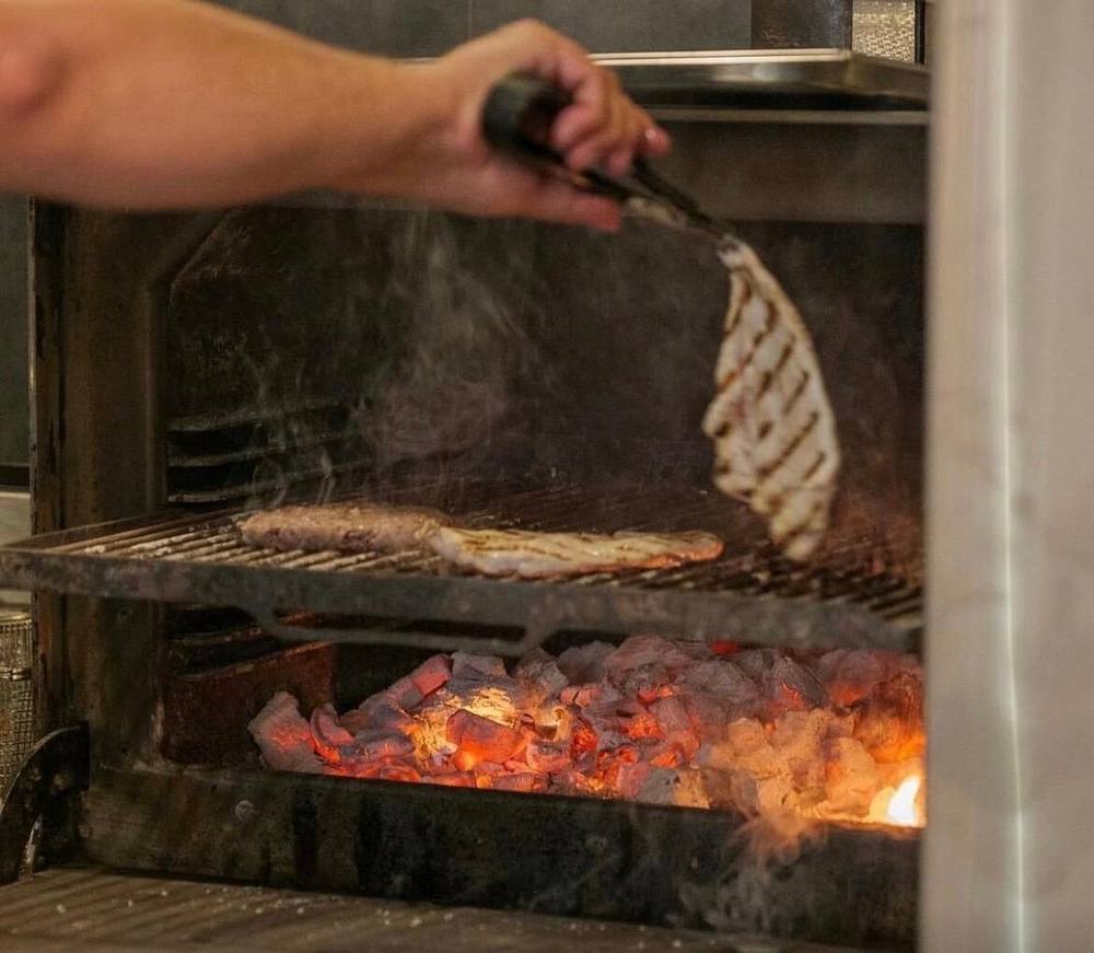 Cooking over charcoal on the grill at Wood Grill at The Queen Adelaide