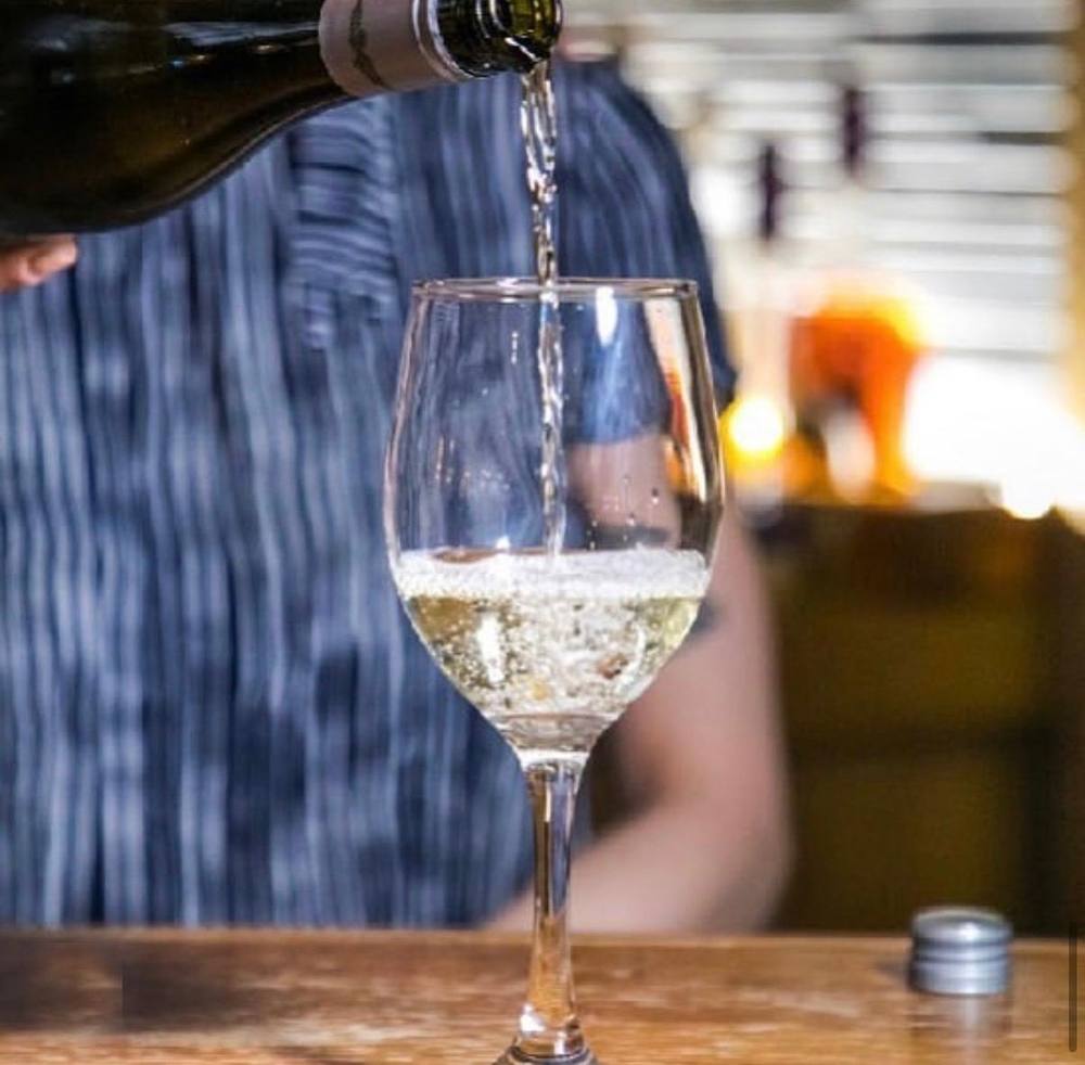 Pouring a glass of white wine at Wood Grill at The Queen Adelaide
